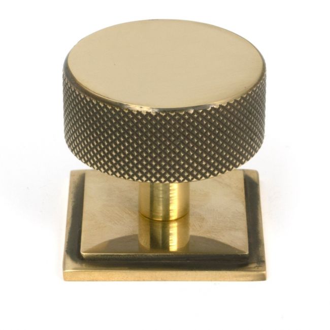 The 38mm Knurled Cabinet Knob on a Square Rose in Aged Brass Shown Upright on a White Background The 38mm Knurled Cabinet Knob on a Square Rose in Aged Brass Shown Upright on a White Background