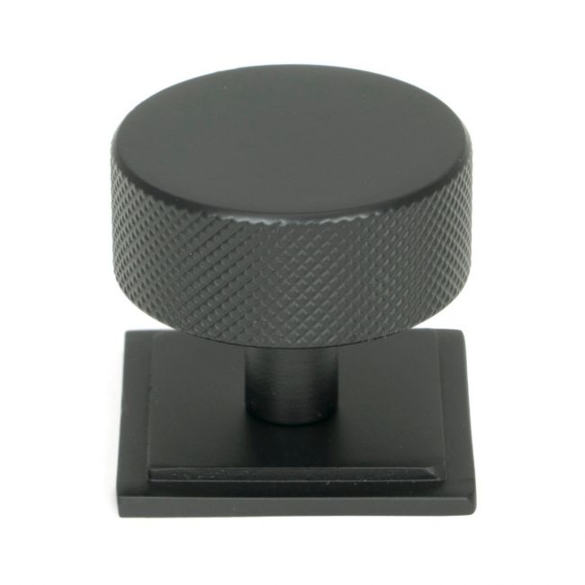 The 38mm Knurled Cabinet Knob on a Square Rose in Matt Black Shown Upright on a White Background