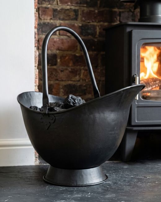 The 58cm "Waterloo" Black Iron Coal Bucket Displayed in a Modern Cream Living Room in Front of a Fireplace - Digital Illustration