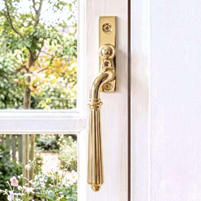 The Left Handed Aged Brass Reeded Georgian Espagnolette Window Handle on a White Background The Left Handed Aged Brass Reeded Georgian Espagnolette Window Handle on a White Background