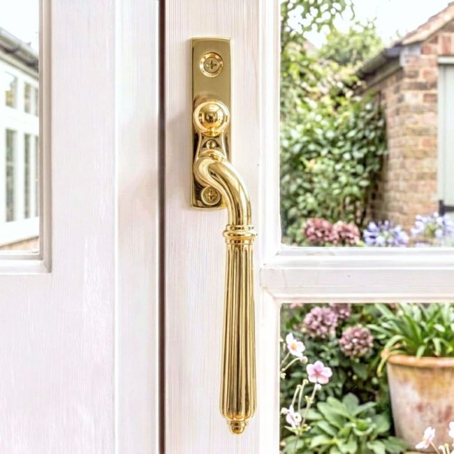 The Right Handed Aged Brass Reeded Georgian Espagnolette Window Handle on a White Background The Right Handed Aged Brass Reeded Georgian Espagnolette Window Handle on a White Background