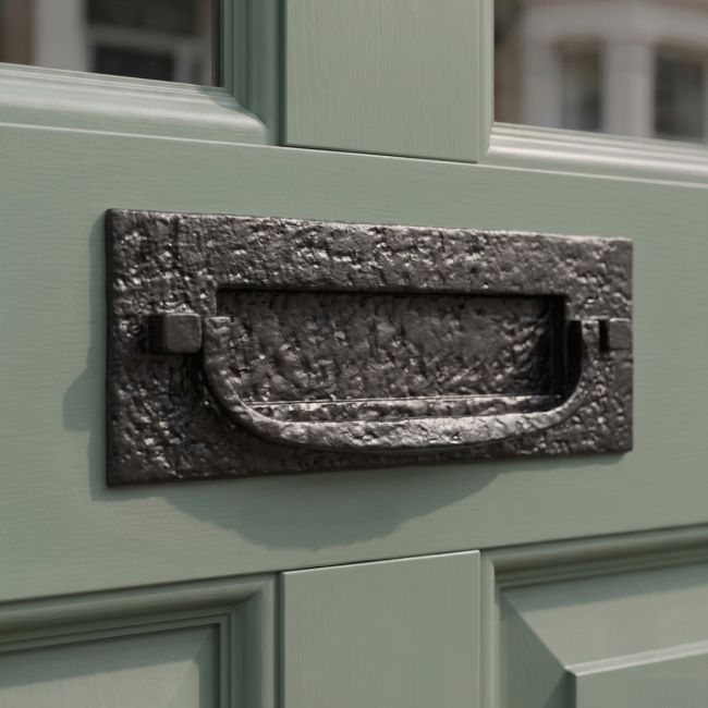 The Antique Black Iron Front Door Letter Plate With Integral Knocker on a Sage Coloured Wooden Door - Digital Illustration