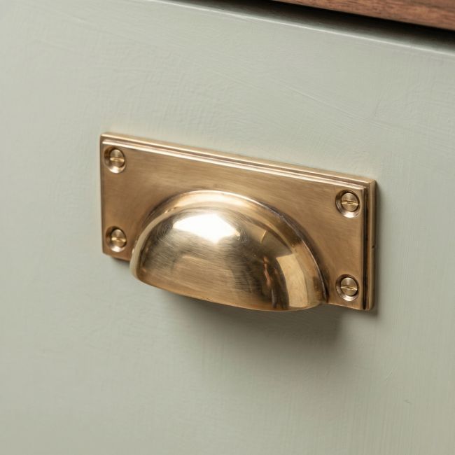 The Art Deco Cup Drawer Pull with Backplate in Aged Brass on a White Background 