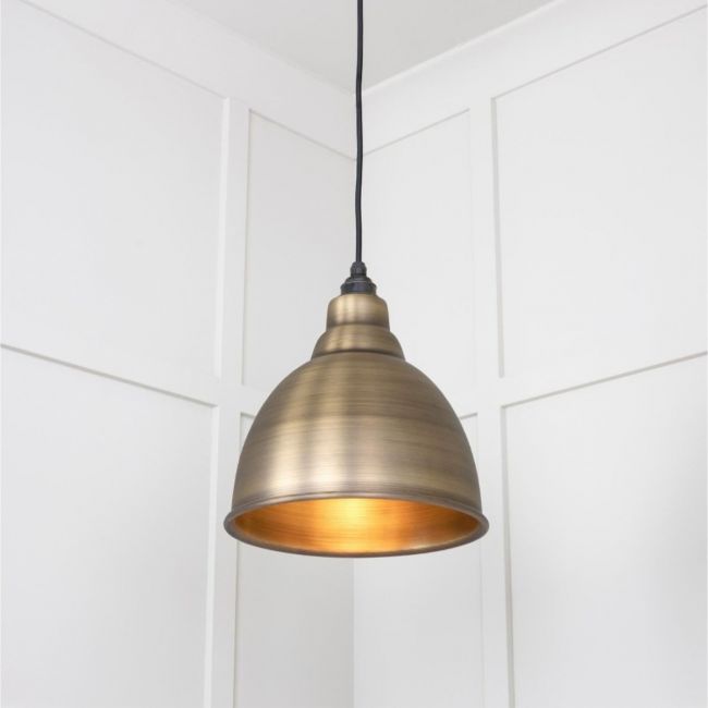 The Aura Dome Pendant Light in Aged Brass Brass Shown Lit Up at a Low Angle