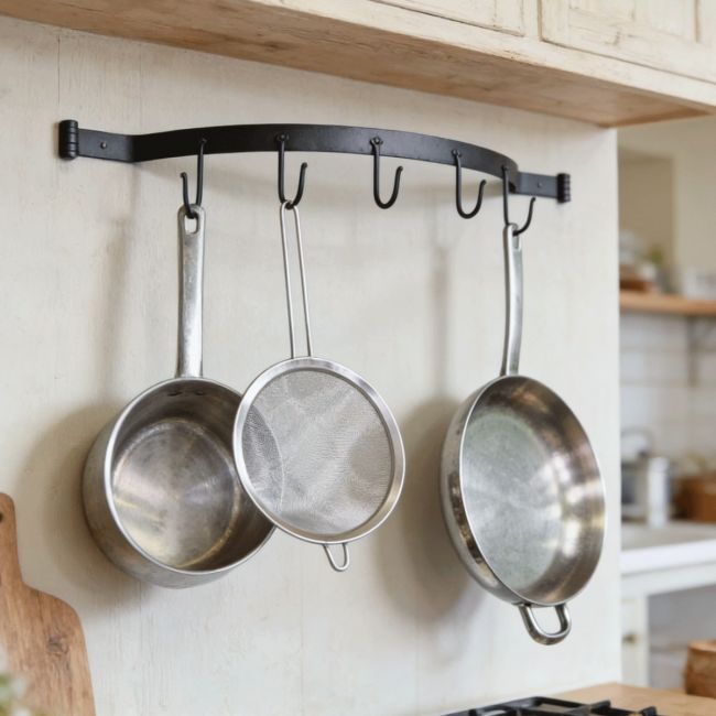 The Blacksmith Wall Mounted Bowed Kitchen Tool Rack Mounted in a Cream Coloured Kitchen with Kitchen Utensils Hanging From it - Digital Illustration