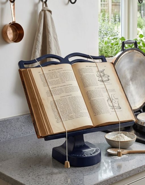 The Blue Cast Iron Cook Book Stand Holding a Recipe Book Open in a Kitchen - Digital Illustration