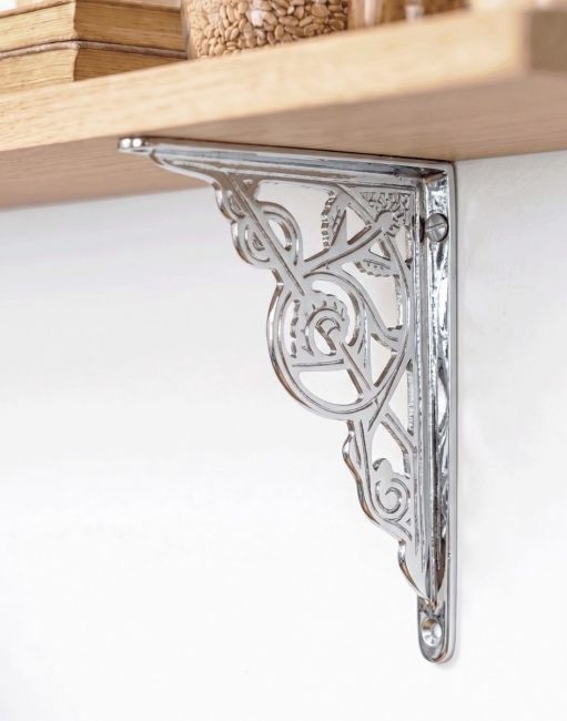 The Bright Chrome Trellis Shelf Bracket in Two Sizes Mounted on a White Coloured Interior Living Room Wall - Digital Illustration 