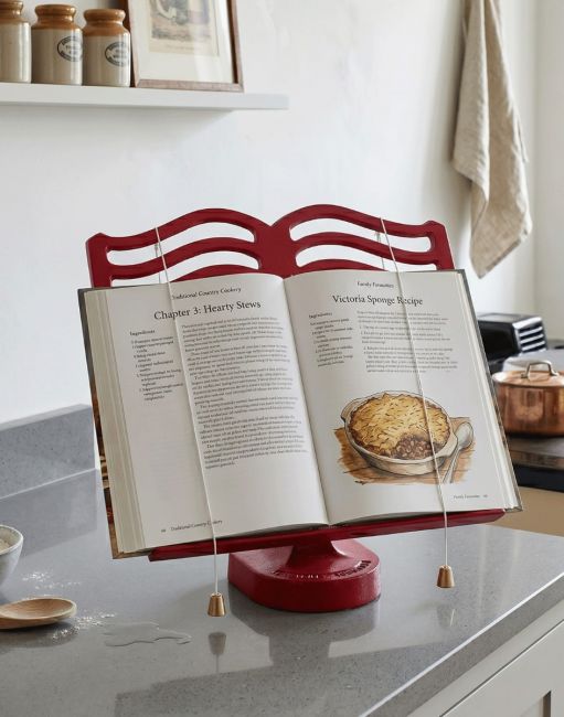 The Cast Iron Cook Book Stand in a Red Finish Holding a Recipe Book in a Modern Kitchen - Digital Illustration
