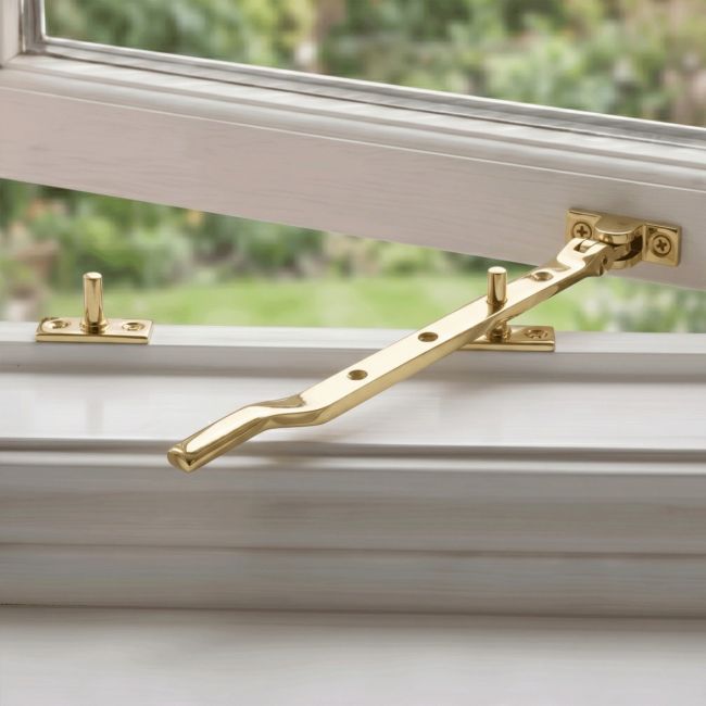 The Contemporary Casement Stay Displayed in a Brass Finish Fitted on a Wooden White Window Frame - Digital Illustration 