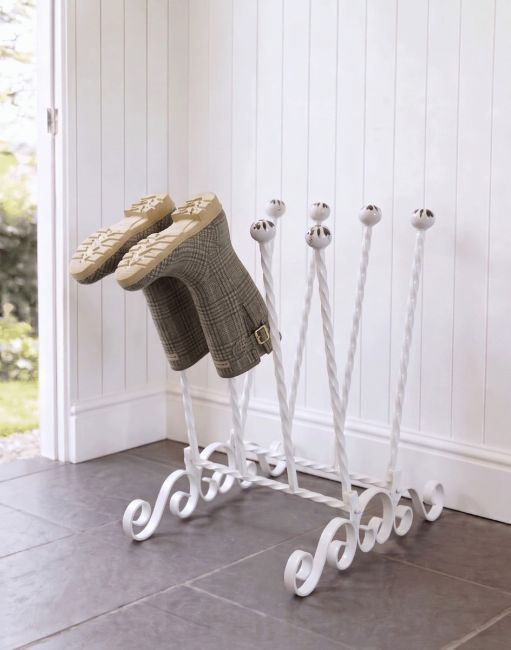 The Evesall Cream 4 Pair Ornate Boot Rack Positioned on a Stone Tile Floor in a Sunny Garden Porch - Digital Illustration 