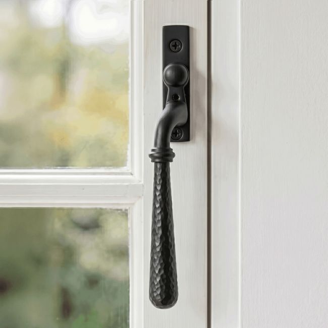 The Left Handed Dark Aged Bronze Hammered Espag Window Handle Mounted on a Traditional White Window Frame in a Country Home - Digital Illustration