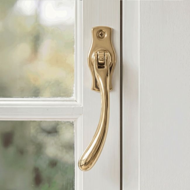 The Left Handed Polished Brass Peardrop Window Handle Screwed onto a Classic White Window Frame in a Contemporary Home - Digital Illustration