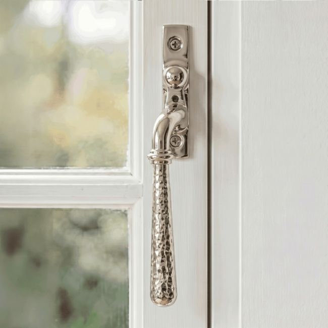 The Left Handed Polished Nickel Hammered Espag Window Handle Fixed on a Painted White Window Frame - Digital Illustration