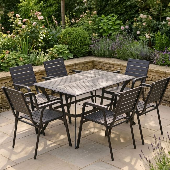 The Linea 6-Seater Outdoor Garden Dining Set in Black in a Sunny Low Walled Garden Surrounded by Plants
