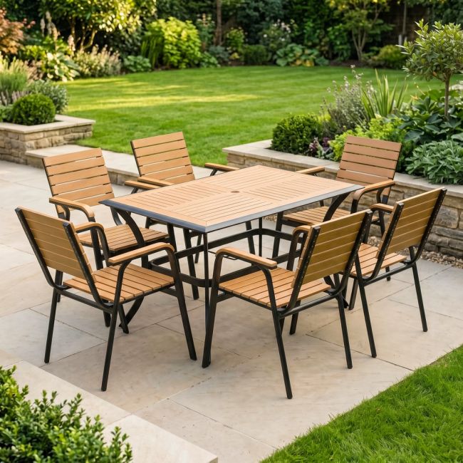 The Linea 6-Seater Outdoor Garden Dining Set in Teak in a Sunny Low Walled Garden Surrounded by Plants