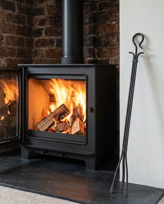 The Long Iron Fireside Tongs Displayed in Front of a Traditional Log Burner in a Country Home - Digital Illustration 