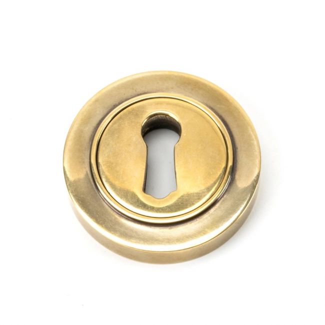 The Plain Concealed Standard Keyhole Escutcheon - Aged Brass on a White Background
