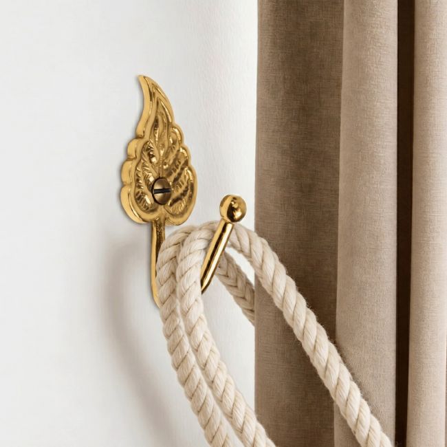 The Polished Brass Curtain Hook in a Leaf Design Fitted on a White Wall in a Modern Interior Home Next to a Brown Curtain - Digital Illustration The Polished Brass Curtain Hook in a Leaf Design Fitted on a White Wall in a Modern Interior Home Next to a Brown Curtain - Digital Illustration