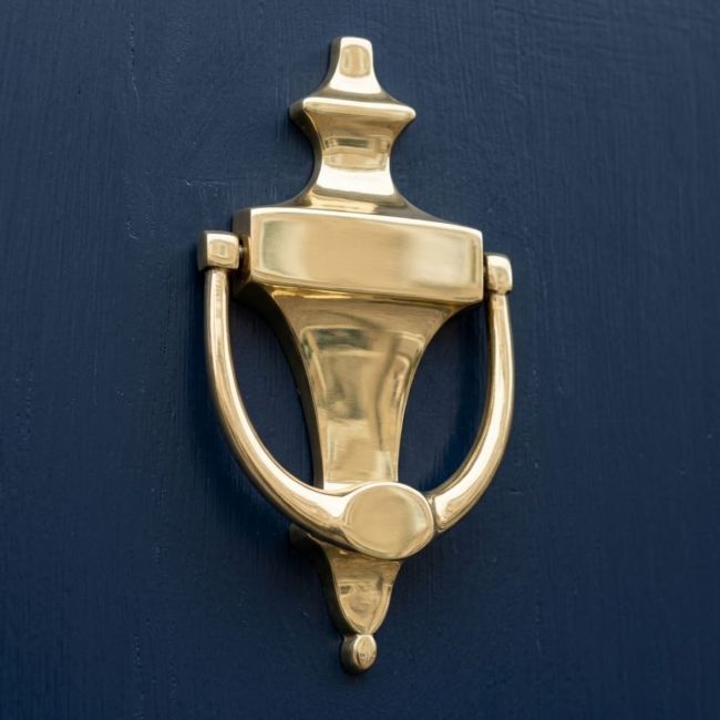 The Polished Brass Edwardian Urn Knockers Shown at an Angle on a Navy Blue Door - Digital Illustration