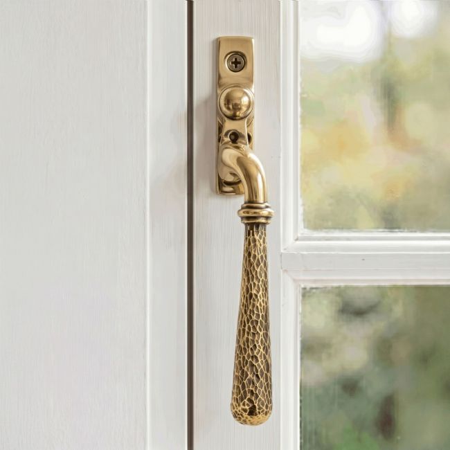 The Right Handed Aged Brass Hammered Espag Window Handle Fitted on a Painted White Window Frame in a Country Home - Digital Illustration 