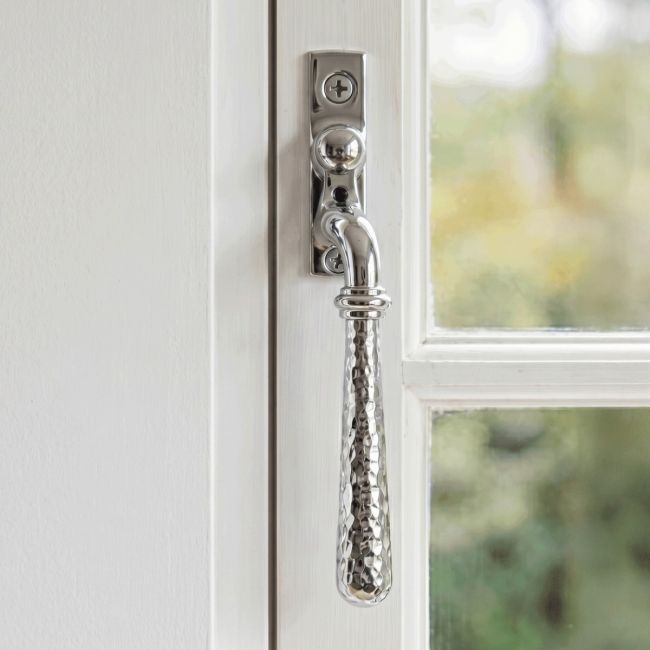 The Right Handed Bright Chrome Hammered Espag Window Handle Mounted on a Classic White Wooden Window Frame - Digital Illustration 