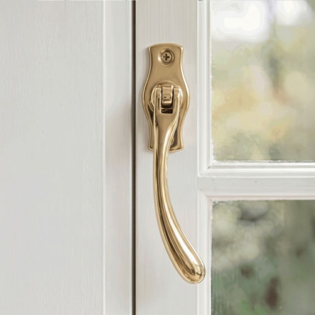 The Right Handed Polished Brass Peardrop Window Handle Screwed onto a Classic White Window Frame in a Contemporary Home - Digital Illustration 