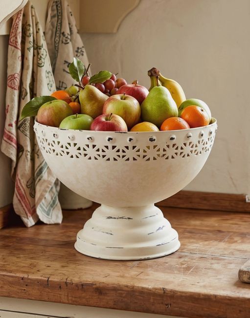 The Shabby Chic White Fruit Bowl Available in a Variety of Sizes Displayed with a Selection of Fruit on a Wooden Kitchen Counter - Digital Illustration 