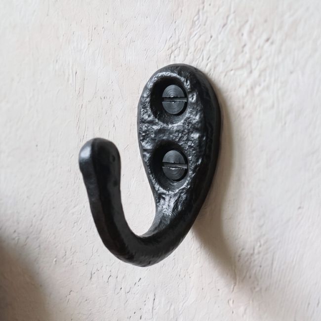 The Small Antique Black Iron Single Wall Coat Hook Shown Close up on a White Wall - Digital Illustration The Small Antique Black Iron Single Wall Coat Hook Shown Close up on a White Wall - Digital Illustration