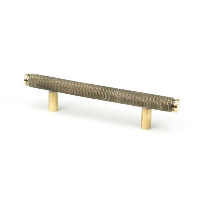 The Small Knurled Cabinet Pull Handle in Aged Brass Shown Upright on a White Background