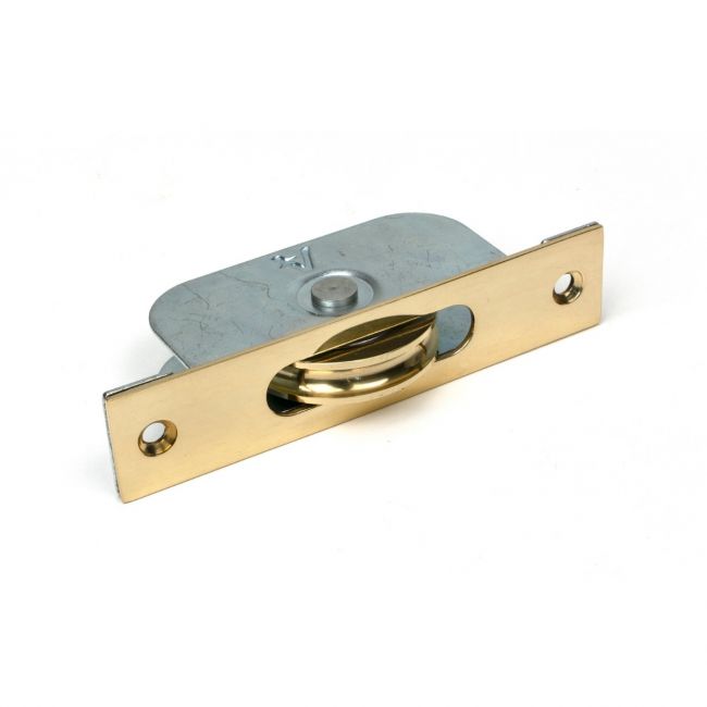 The Square Ended Sash Window Pulley (75kg) in Polished Brass Shown on its Side on a White Background