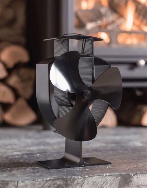 The Three Blade Heat Powered Stove Fan Displayed in a Modern Living Room with a Lit Log Burner Stove Behind - Digital Illustration The Three Blade Heat Powered Stove Fan Displayed in a Modern Living Room with a Lit Log Burner Stove Behind - Digital Illustration