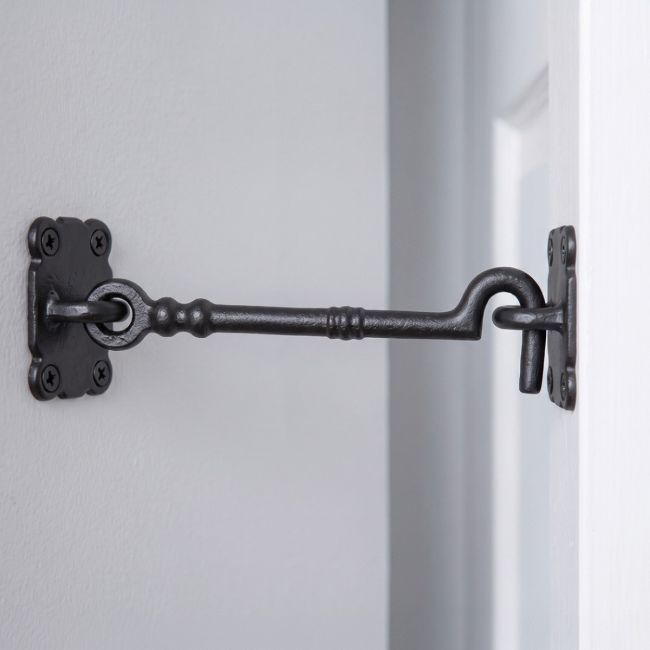 The Traditional Black Iron Large 16" Loose Ring Cabin Hook Fitted on a White Door next to a Grey Coloured Interior Wall - Digital Illustration