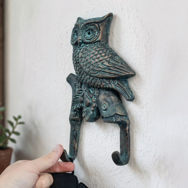 The Verdigris Owl Double Hook on a White Wall with a Hand in Shot for Scale - Digital Illustration The Verdigris Owl Double Hook on a White Wall with a Hand in Shot for Scale - Digital Illustration