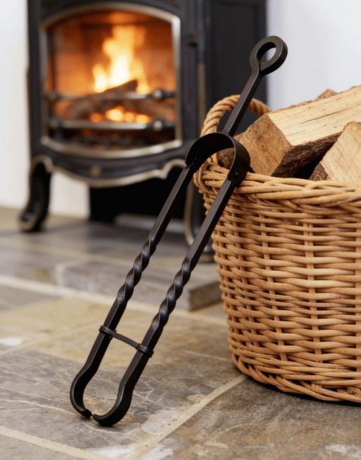 The Wrought Iron Tongs with Safety Clip on a Stone Tiled Cottage Floor in Front of a Lit Log Burner Stove - Digital Illustration The Wrought Iron Tongs with Safety Clip on a Stone Tiled Cottage Floor in Front of a Lit Log Burner Stove - Digital Illustration
