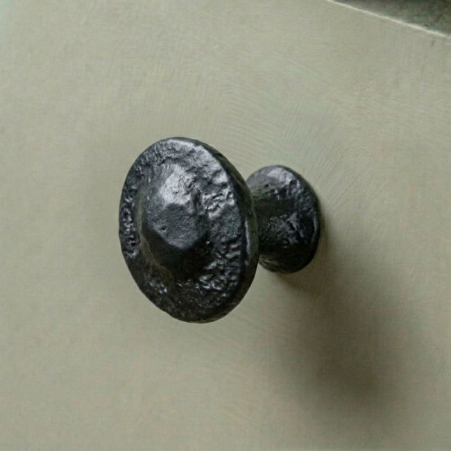 Traditional Black Iron Button Design Cabinet or Cupboard Knob Mounted on a Green Kitchen Cupboard Door - Digital Illustration 