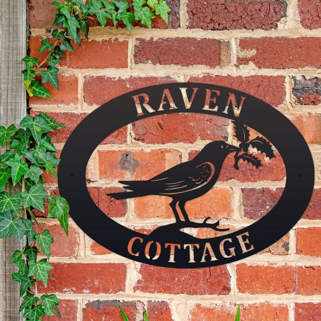 Raven & Holly Iron Oval House Sign on a Brick Wall