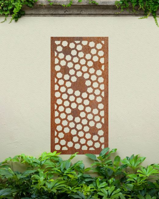 Rustic" Honeycomb Pattern Wall Art" on a cream garden wall behind garden plants Rustic" Honeycomb Pattern Wall Art" on a cream garden wall behind garden plants