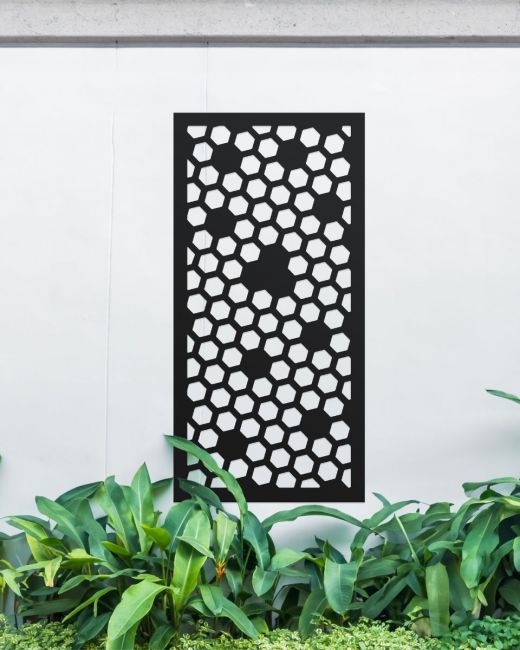 Black "Honeycomb Pattern Wall Art" mounted on a white garden wall surrounded by garden plants Black "Honeycomb Pattern Wall Art" mounted on a white garden wall surrounded by garden plants