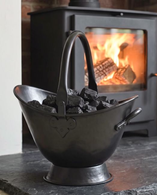 The 43cm "Waterloo" Black Iron Coal Bucket Placed on a Stone Tile Floor in Front of a Log Burner Stove - Digital Illustration 