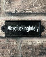 "Absofuckinglutely" Traditional Cast Iron Wall Sign mounted on a brick wall