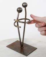 "Embrace" Upcycled Metal Art Ornament with hand in shot for scale