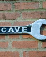"Man Cave" Spanner Sign in Cast Aluminium Wall Art Mounted on a Brick Wall Close up of Right Side "Man Cave" Spanner Sign in Cast Aluminium Wall Art Mounted on a Brick Wall Close up of Right Side