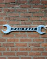 "Man Cave" Spanner Sign in Cast Aluminium Wall Art Mounted on a Brick Wall with Hand in Shot for Scale "Man Cave" Spanner Sign in Cast Aluminium Wall Art Mounted on a Brick Wall with Hand in Shot for Scale