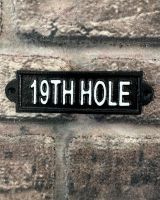 "Nineteenth Hole" Traditional Cast Iron Wall Sign mounted on a brick wall
