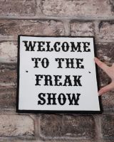 Humorous Cast Iron Wall Sign - “Welcome to the Freak Show” to scale with hand for reference