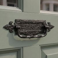 A 14 Inch Traditional Black Iron Fleur-De-Lys Letter Plate With Integral Knocker Mounted on a Sage Green Timber Front Door - Digital Illustration A 14 Inch Traditional Black Iron Fleur-De-Lys Letter Plate With Integral Knocker Mounted on a Sage Green Timber Front Door - Digital Illustration