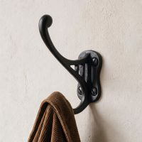 A Black Bayswater Iron Coat Hook Polished Mounted on a Textured Hallway Wall with a Coat on it - Digital Illustration 
