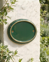A Blank Brass & Green Oval House Number Plaque Mounted on a Cream Coloured Building Wall - Digital Illustration 