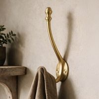A Close up of a 86mm Satin Brass Double Hat & Coat Hook Holding a Jacket Mounted on a Wall - Digital Illustration A Close up of a 86mm Satin Brass Double Hat & Coat Hook Holding a Jacket Mounted on a Wall - Digital Illustration