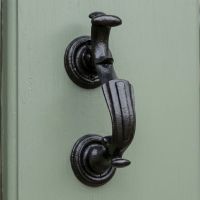 A Close up of the "Belgrave Manor" Cast Iron Victorian Door Knocker on a Sage Green Door - Digital Illustration